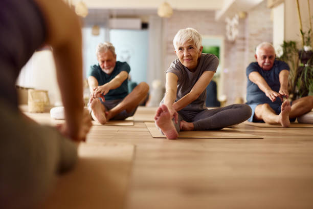 Groupe de personnes d'âge mûr effectuant des exercices d'étirement. Le plan se concentre sur une femme âgée.